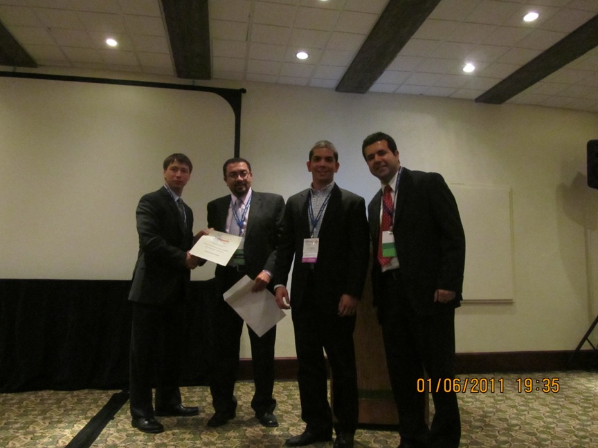 Andrew Tomchek receiving the 2nd Place, Phononics 2011 NSF Best Student Poster Presentation Award from the conference chairs. Also shown is Edgar Flores who collaborated with Andrew in his research.